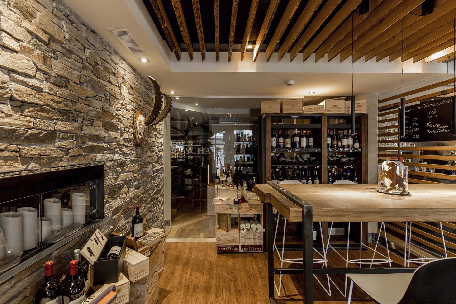Elegante Bar mit Steinwand, grossem Weinregal und Sitzbereich