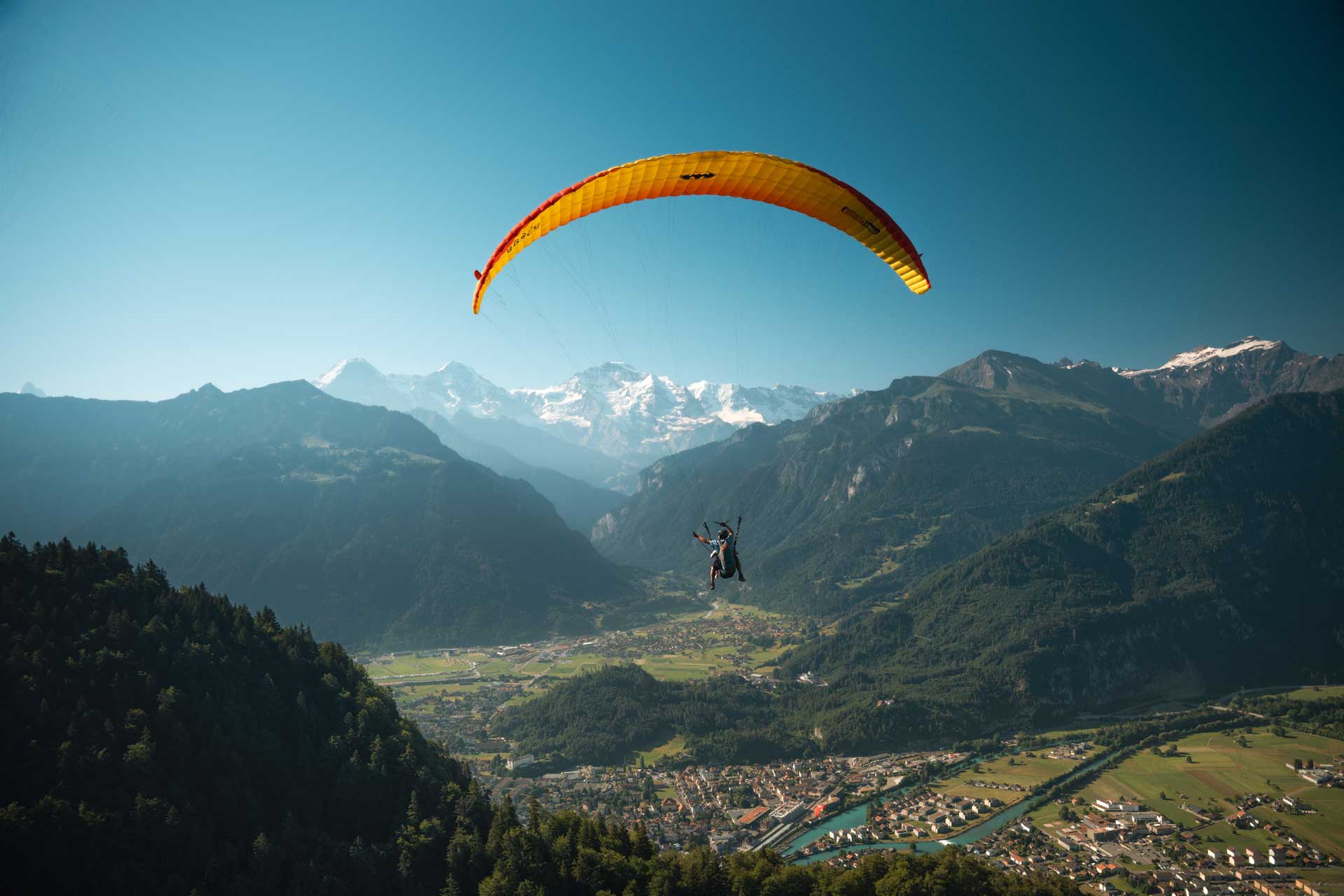 Eine Person geniesst einen Gleitschirmflug inmitten der Berge