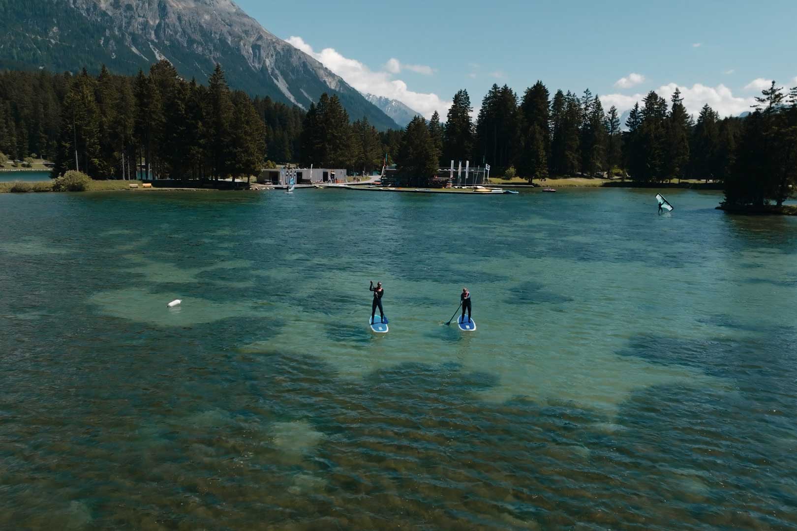 Zwei Freunde paddeln mit dem SUP auf dem Heidsee vor dem Wassersportzentrum