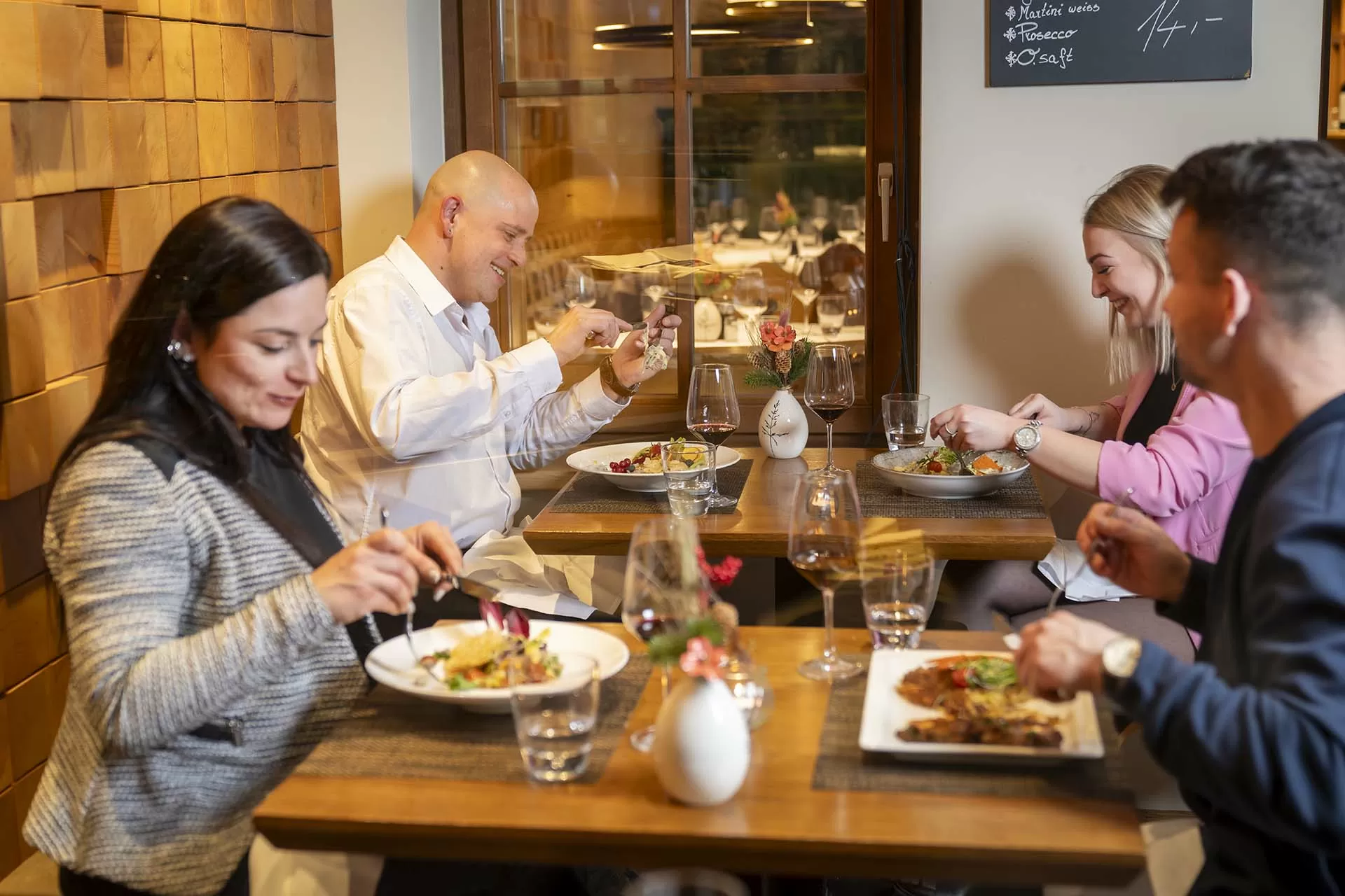 Vier Gäste geniessen ein feines Abendessen im Restaurant Speschai im Hotel Lenzerhorn