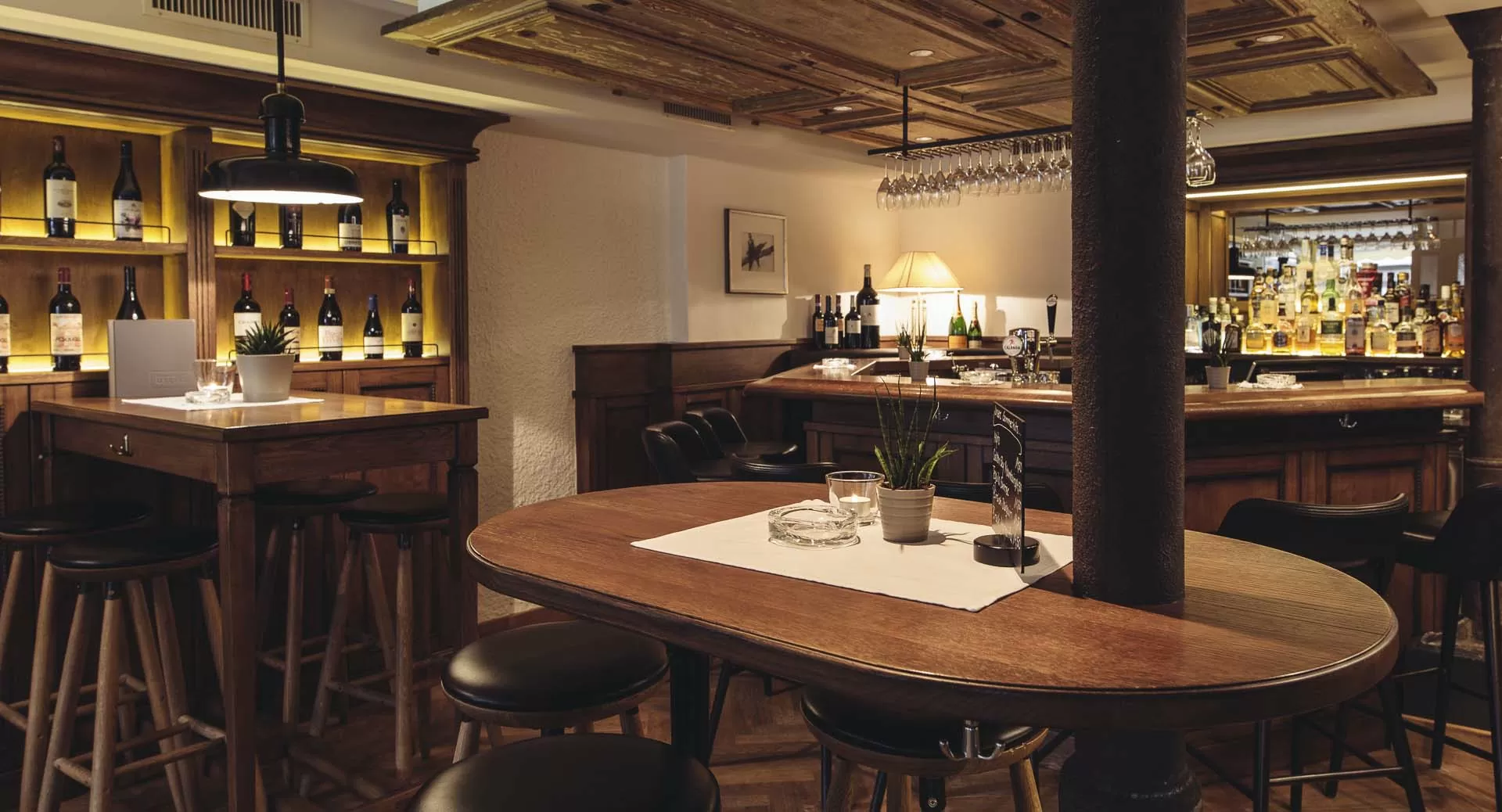 Modernes Barambiente mit Steinmauer, Weinregal und Tischen in gemuetlicher Atmosphaere